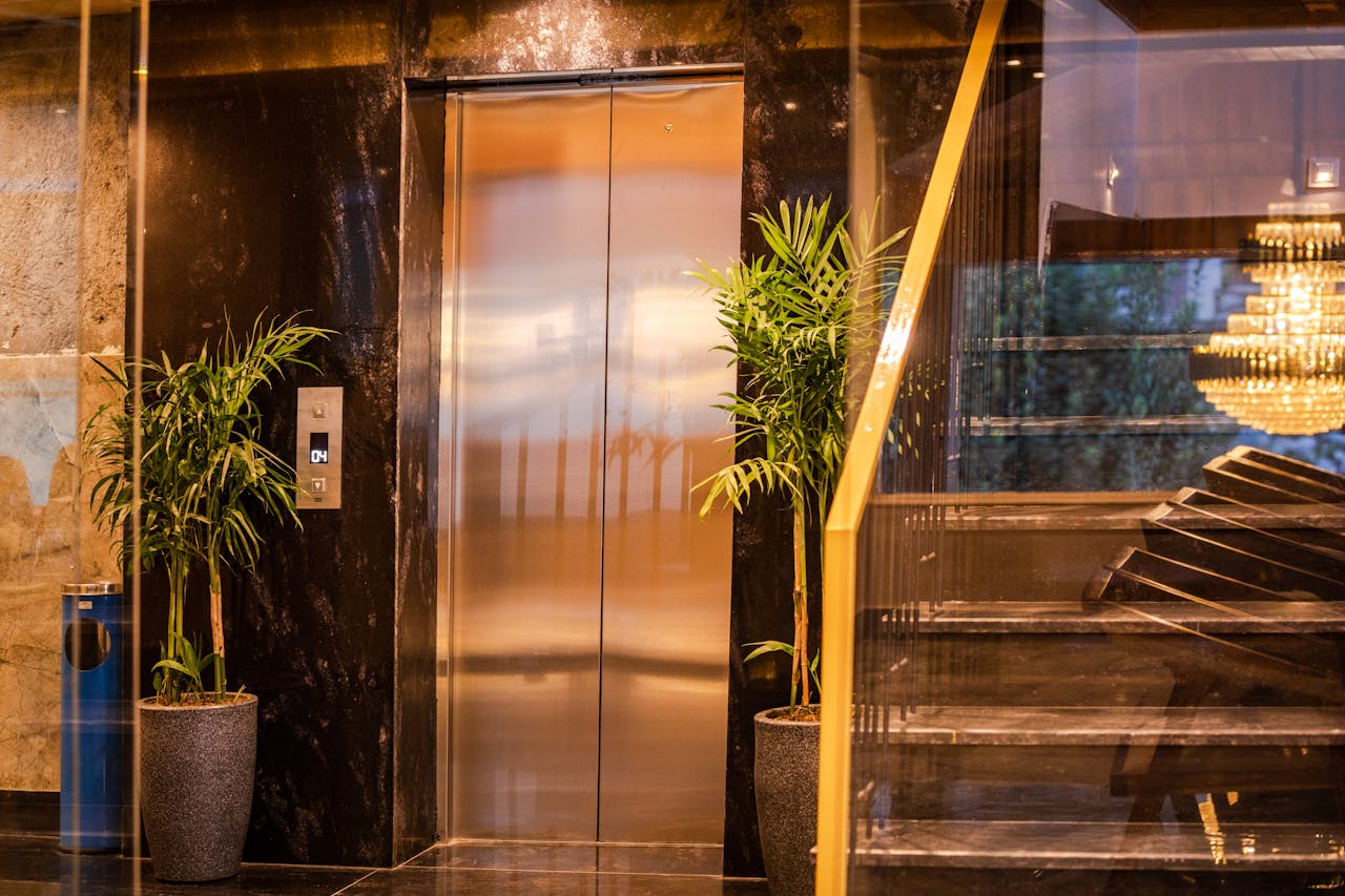 Elegant hotel elevator with lush plants and modern staircase, reflecting luxury and sophistication.